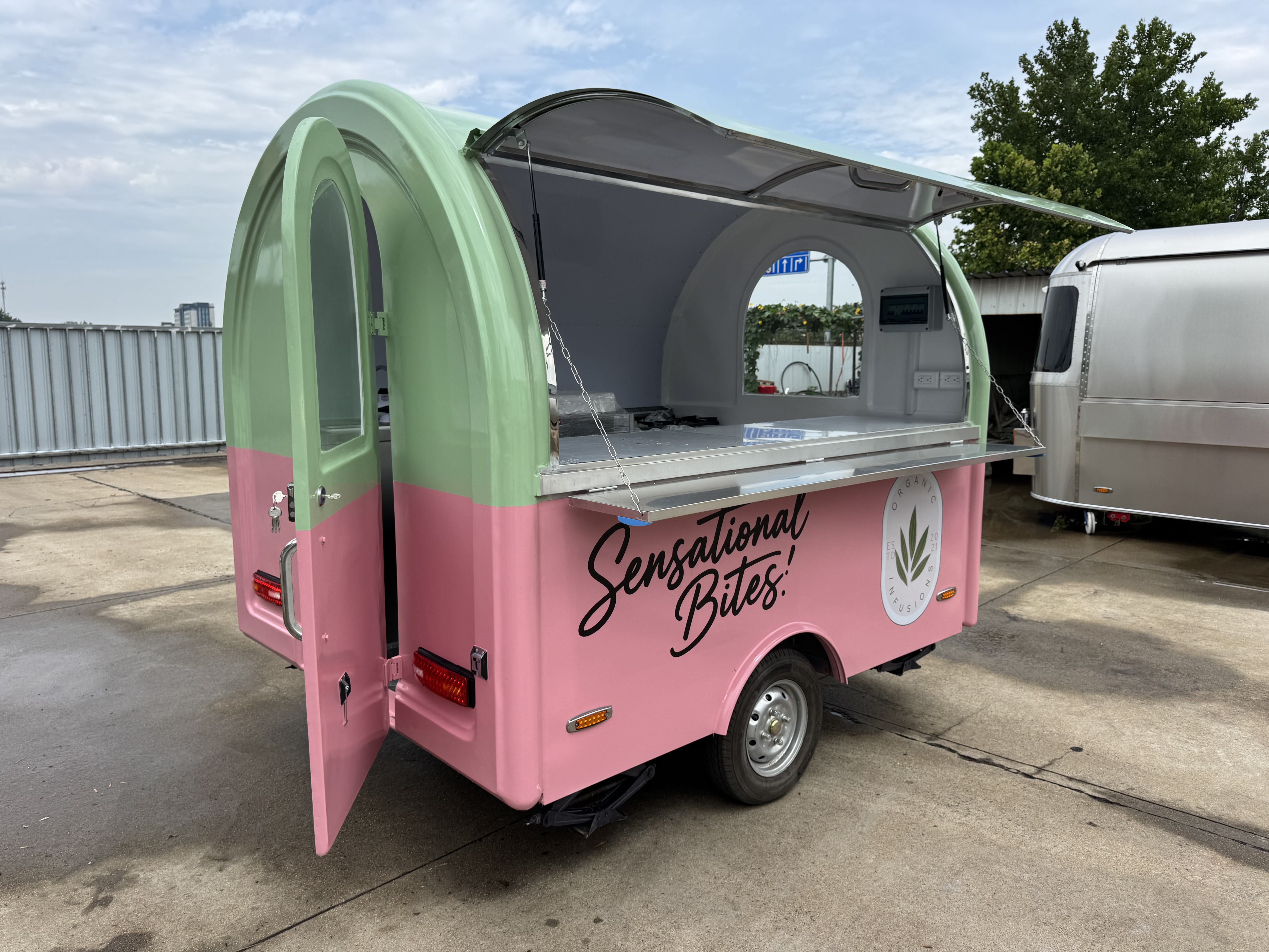 A mobile food truck with a combination of pink and green and colors, brimming with girlish charm