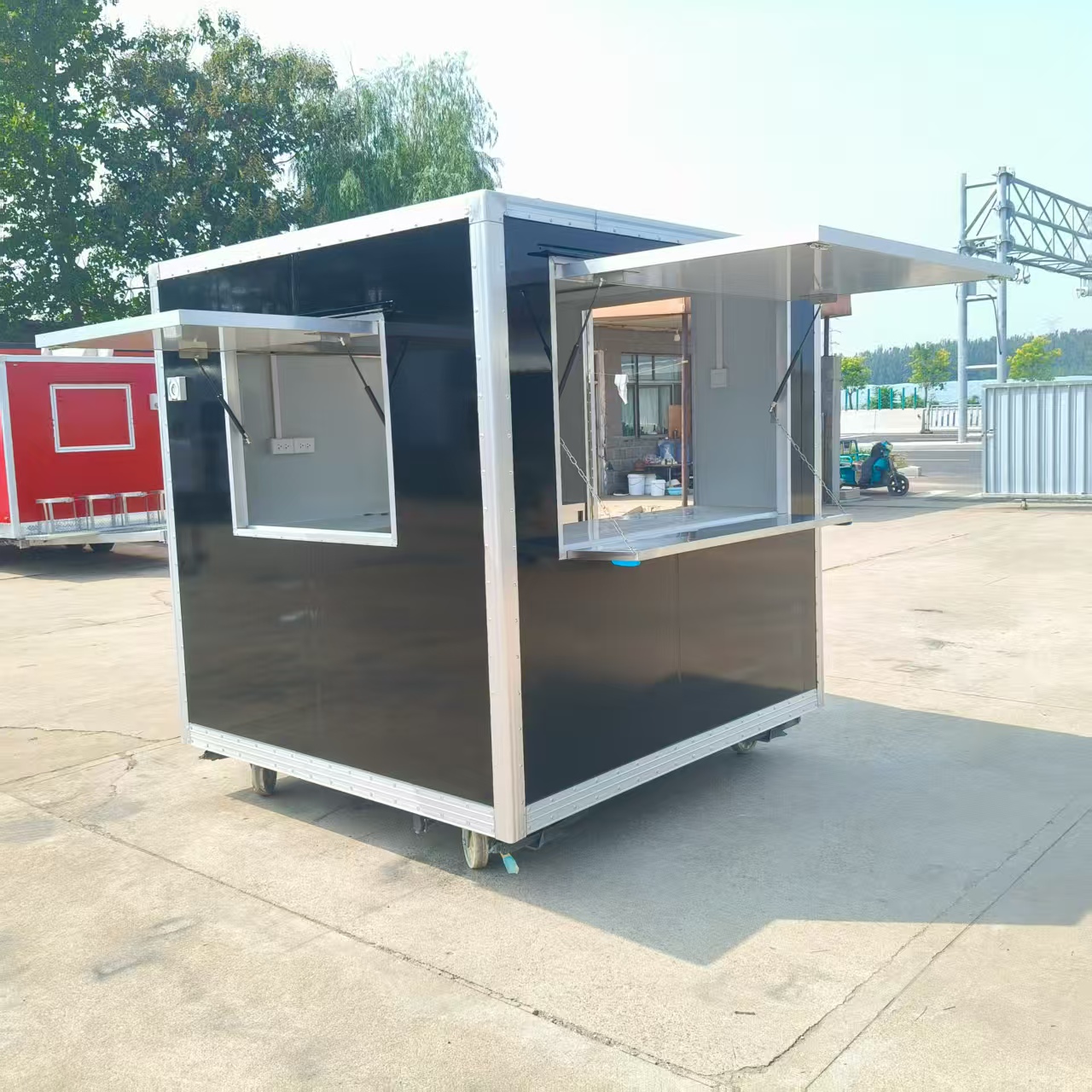 A wheeled, mobile black food truck with a window, an outdoor snack cart, and a multi-functional food truck
