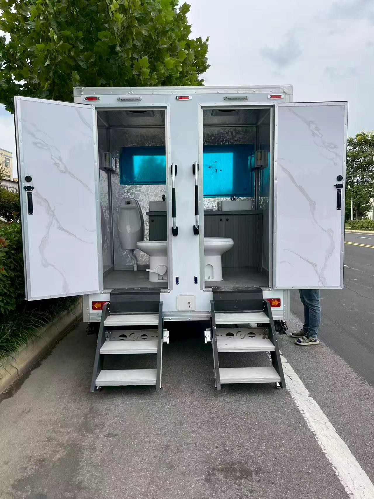 A portable multi-compartment bathroom trailer with a white appearance for mobile toilets