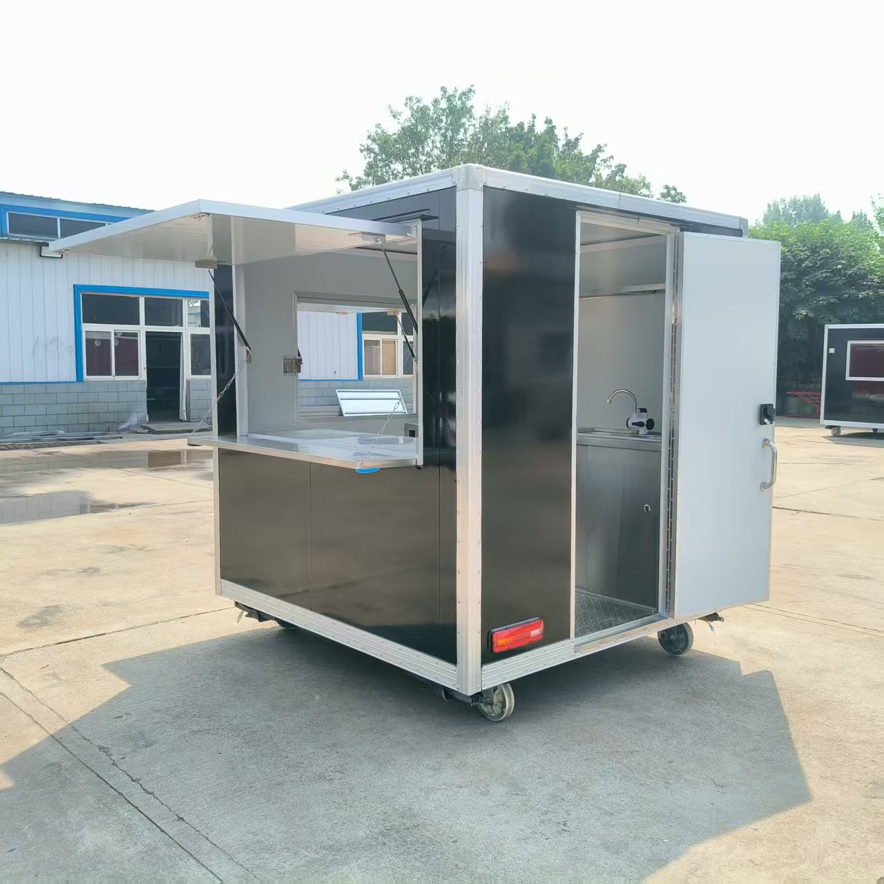 A wheeled, mobile black food truck with a window, an outdoor snack cart, and a multi-functional food truck