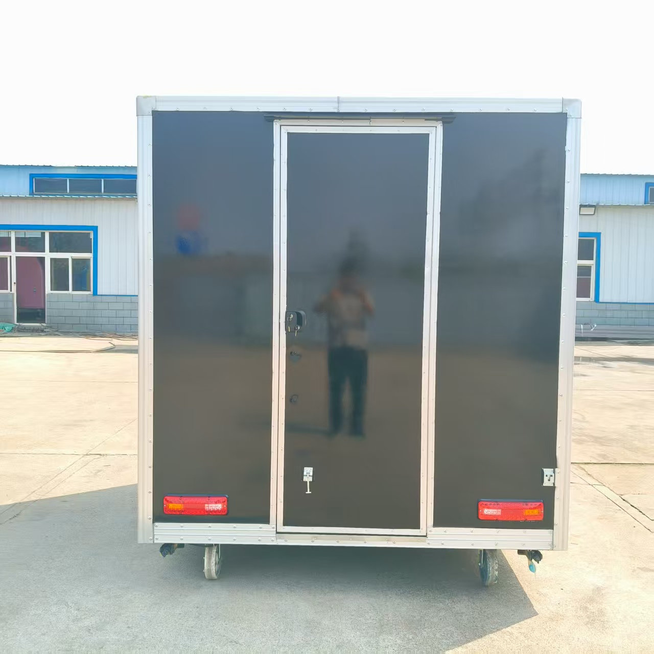 A wheeled, mobile black food truck with a window, an outdoor snack cart, and a multi-functional food truck