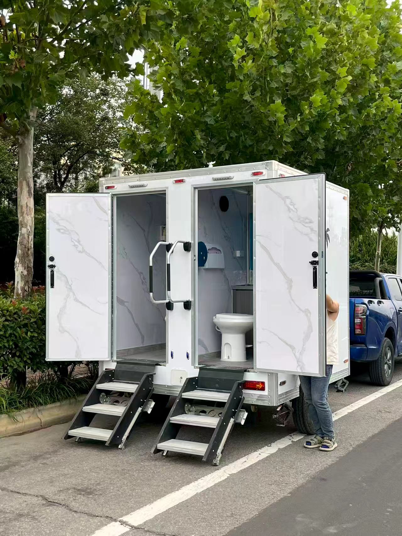 A portable multi-compartment bathroom trailer with a white appearance for mobile toilets