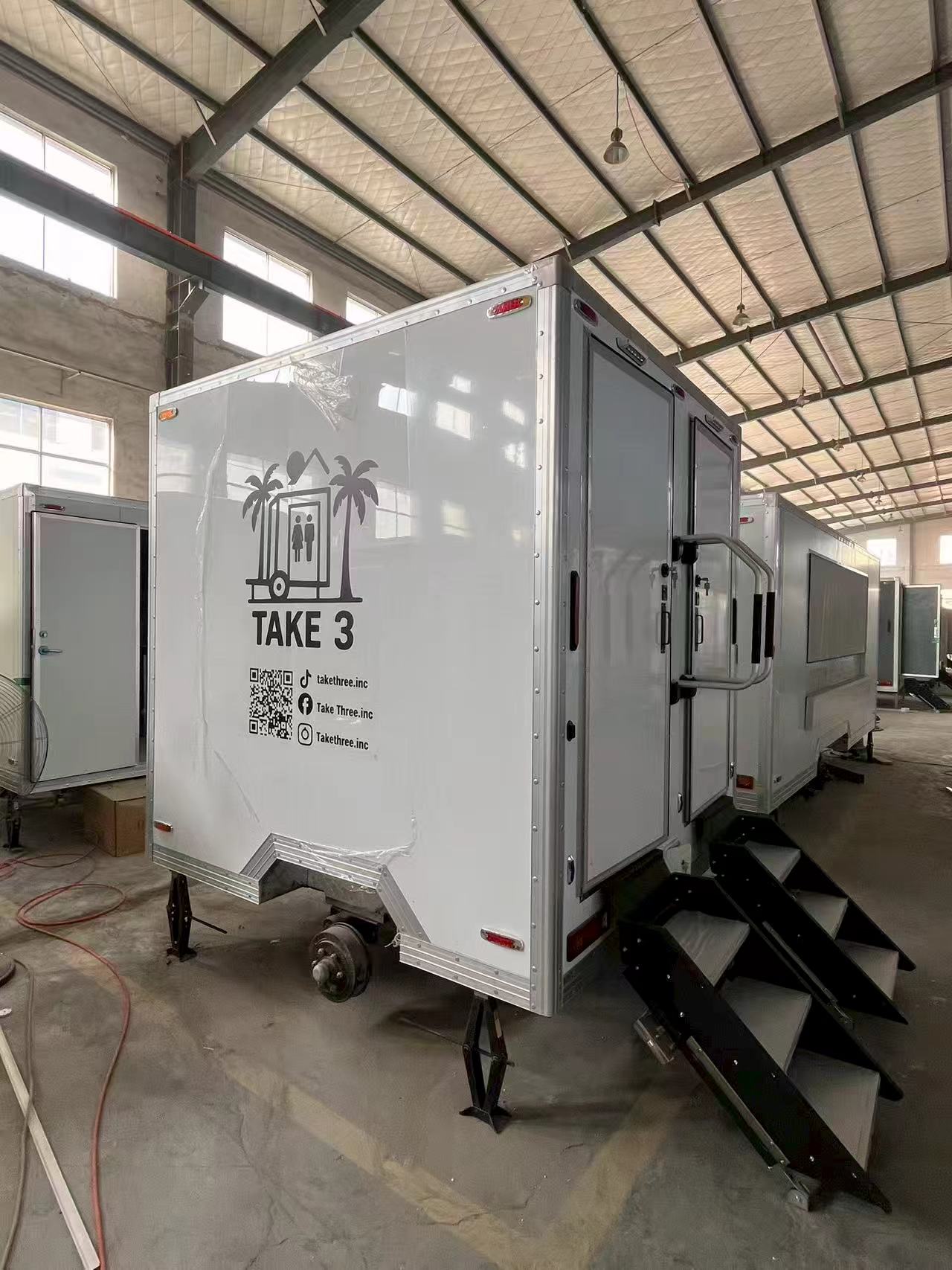 A portable multi-compartment bathroom trailer with a white appearance for mobile toilets